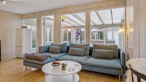 Ein modernes Wohnzimmer mit einem großen grauen Ecksofa, einem weißen Couchtisch und einem weißen Kühlschrank.