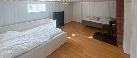 A bedroom with a large bed, a smaller bed, a desk, and a chair.