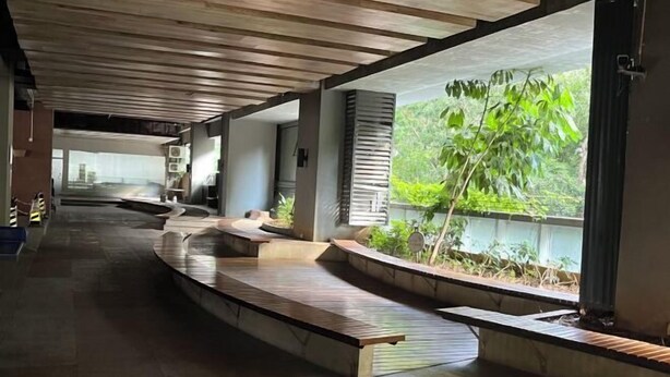 A modern interior with a curved seating area, large windows, and a view of greenery outside. - Pinwu Apartment (Shenzhen)