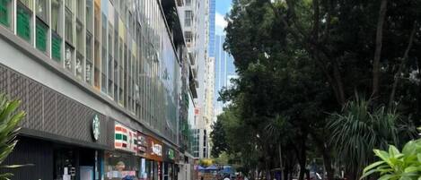 A street lined with modern buildings, a Starbucks, and pedestrians.