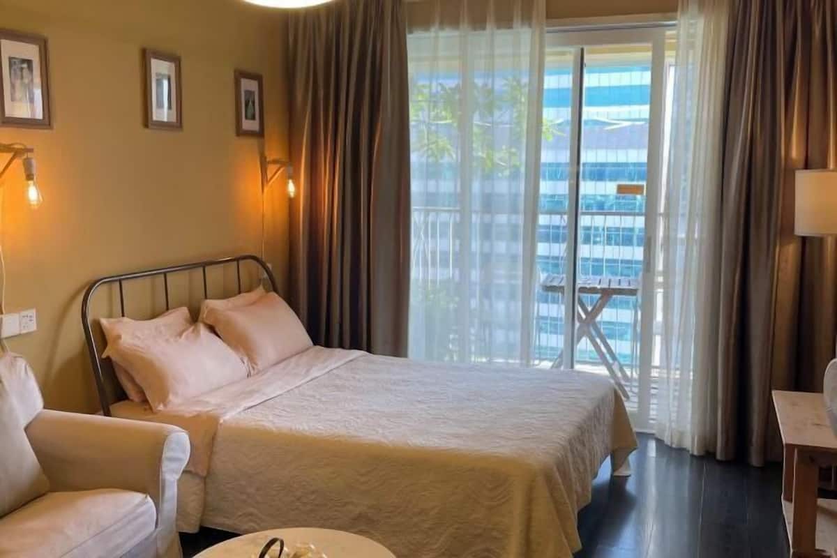 Quarto de hotel com cama, cadeira, mesa e varanda com vista para a cidade.