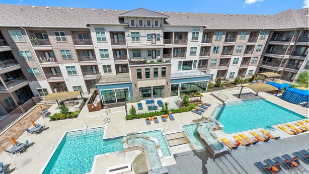 Un hôtel à plusieurs étages doté d’un espace piscine sur le toit, comprenant plusieurs piscines, des chaises longues et un jardin aménagé.