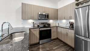 Une cuisine moderne dotée d’appareils électroménagers en acier inoxydable, d’armoires en bois et d’un plan de travail en granit.