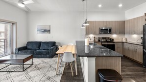 Une cuisine moderne dotée d’un îlot central, d’appareils électroménagers intégrés et d’un coin repas comprenant un canapé et des chaises.