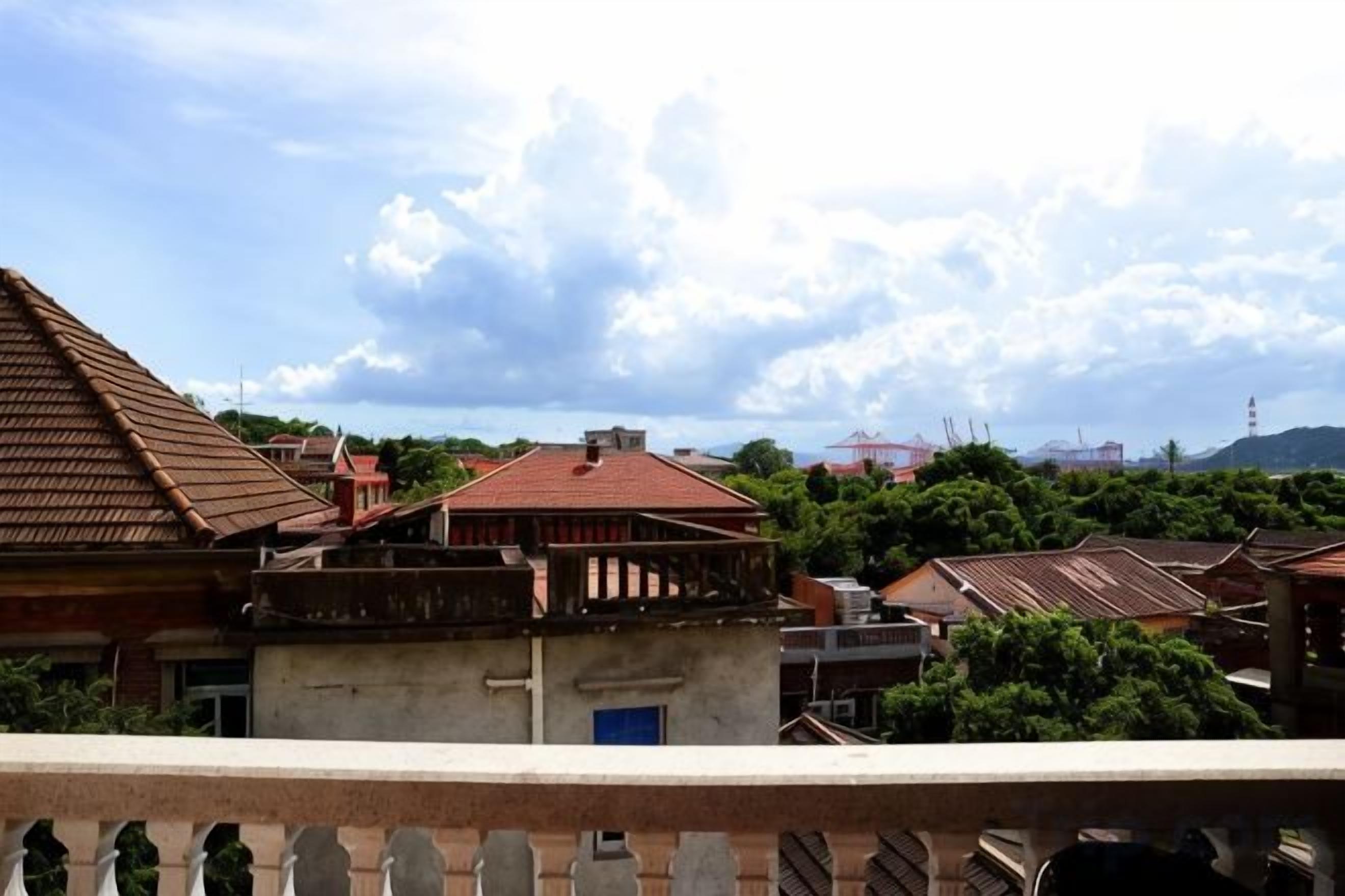 A residential area with multiple buildings, including a house with a red roof and a balcony.