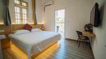 A bedroom with a bed, bedside table, chair, and a TV mounted on the wall.