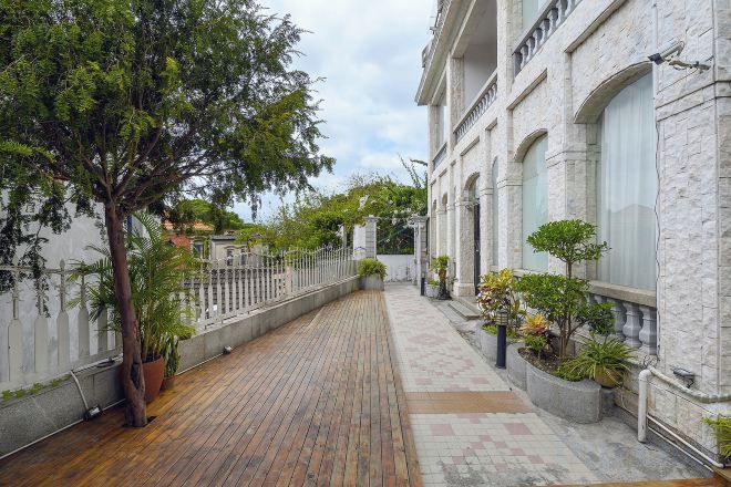 A courtyard with a wooden floor, a white fence, and potted plants.