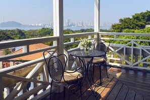 A balcony with a table and chairs, overlooking a cityscape and greenery. - Gulangyu Qihai Homestay (Xiamen)