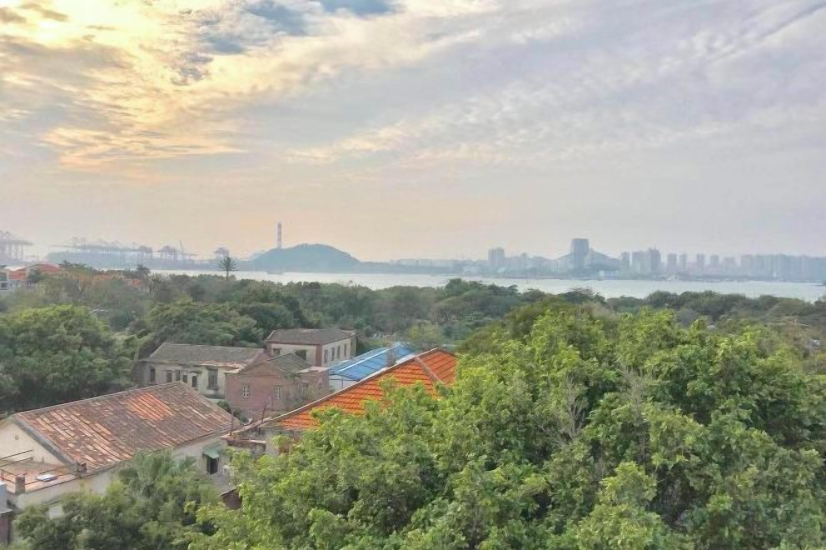 A view of a coastal area with buildings, trees, and a distant city skyline.