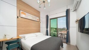 Une chambre d’hôtel moderne, équipée d’un lit, d’un bureau et d’une chaise. Une grande fenêtre, agrémentée de rideaux, offre une vue sur l’extérieur.