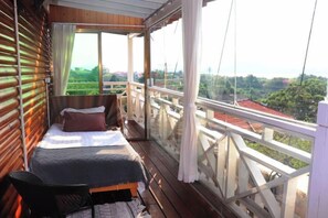 A balcony with a bed, a chair, and a view of greenery. - Gulangyu Qihai Homestay (Xiamen)