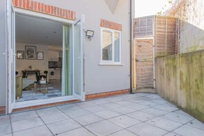 Ein Wohnhaus mit Schiebetür, einer kleinen Terrasse und einer sichtbaren Küche inklusive Waschmaschine.