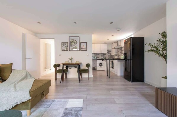 Eine moderne Wohnung mit Essbereich, Küche und Wohnzimmer mit Sofa und Couchtisch.