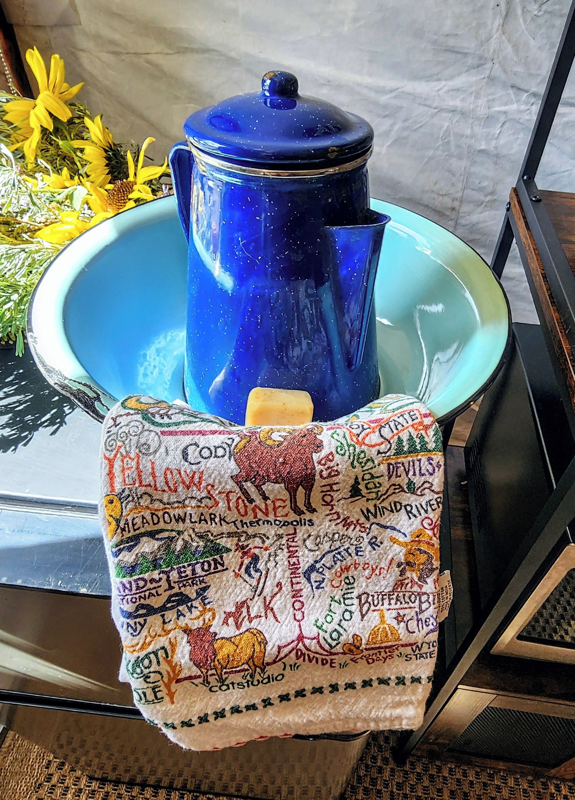 A blue pot on a teal tray with a cloth featuring various place names and symbols.