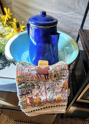 Un pot bleu posé sur un plateau turquoise, sur lequel est disposée une étoffe ornée de différents noms de lieux et de symboles.