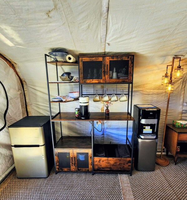 A compact kitchenette with a coffee maker, a small fridge, and a water dispenser.