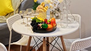 A round table with a fruit bowl, wine glasses, and a vase of flowers. - Ramblei near Chinatown & CenterCity: 2-Bedroom - Unit C (Philadelphia)