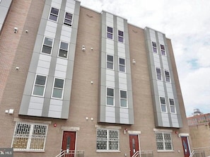 A multi-story building with a brick facade, large windows, and red doors.