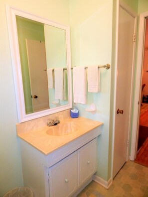 Une salle de bain avec un lavabo, un miroir et deux serviettes suspendues à un porte-serviettes.