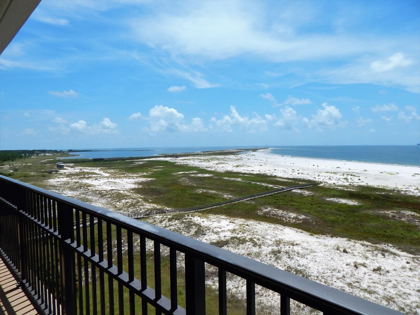 A balcony with a view of a beach and a distant island.