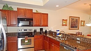 A modern kitchen with wooden cabinets, stainless steel appliances, granite countertops, and a dishwasher.