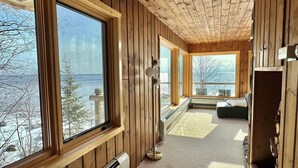 A cabin with large windows, a cozy seating area, and a view of the outdoors.