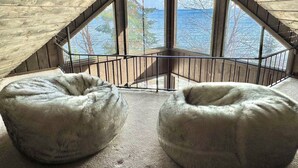 A room with a sloped ceiling, large windows, and two bean bags.