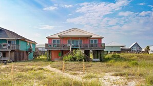 A beachfront house with a balcony, a covered porch, and a sandy surrounding. - Beautiful bayfront home with views of the Dauphin Island Bridge (Dauphin Island)