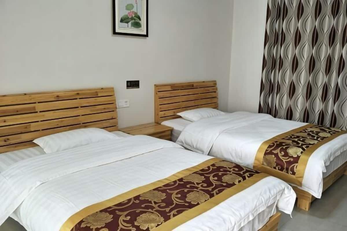Two twin beds with wooden headboards, white bedding, and a patterned bedspread.