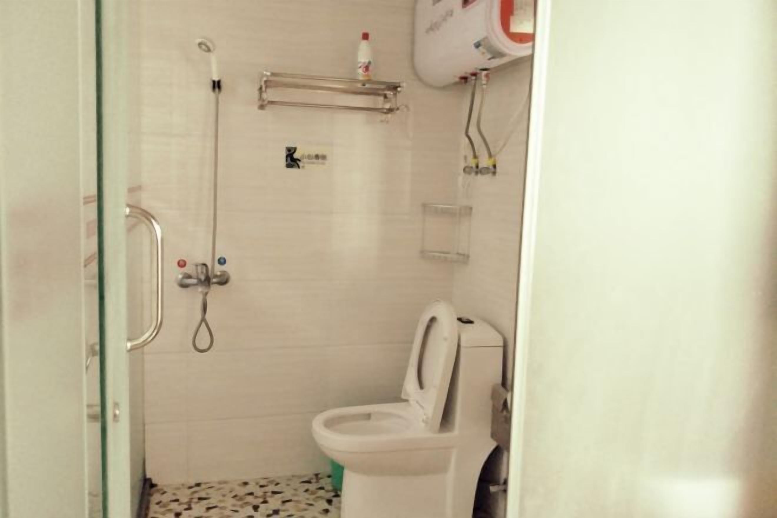 A small, compact bathroom with a toilet, a shower, and a glass-enclosed shower stall.