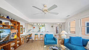 A spacious living room with a blue sofa, a glass coffee table, and a wooden bookshelf.