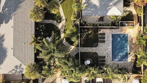 Vue aérienne d’une propriété dotée d’une piscine, d’un jardin aménagé et d’un patio couvert.