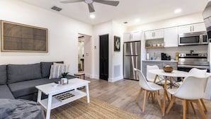 Een moderne woonkamer met een grijze bank, een witte salontafel en een plafondventilator.