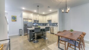 A modern kitchen with stainless steel appliances, a bar area, and a dining table with chairs. - 2-in-1 Home! Entire Duplex for Your Private Stay (Memphis)