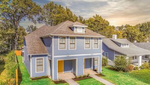 A two-story house with a garage, surrounded by a well-maintained lawn and trees. - 2-in-1 Home! Entire Duplex for Your Private Stay (Memphis)