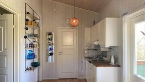 A kitchen with wooden cabinets, a sink, and a hanging light fixture. - 1 bedroom cozy home in Färjestaden (Färjestaden)