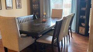 A dining area with a dark wooden table, cushioned chairs, and a hanging light fixture.
