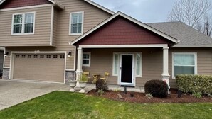 A two-story house with a garage, a front porch with chairs, and a well-maintained lawn.
