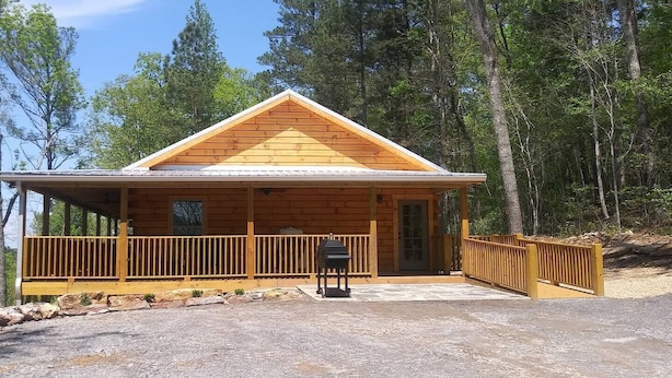 Een houten hut met een veranda, een deur en een schoorsteen.