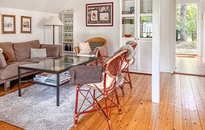 A living room with a glass coffee table, a sofa, wicker chairs, and a dining area with a white cabinet. - 3 bedroom gorgeous home in Højby (Højby)