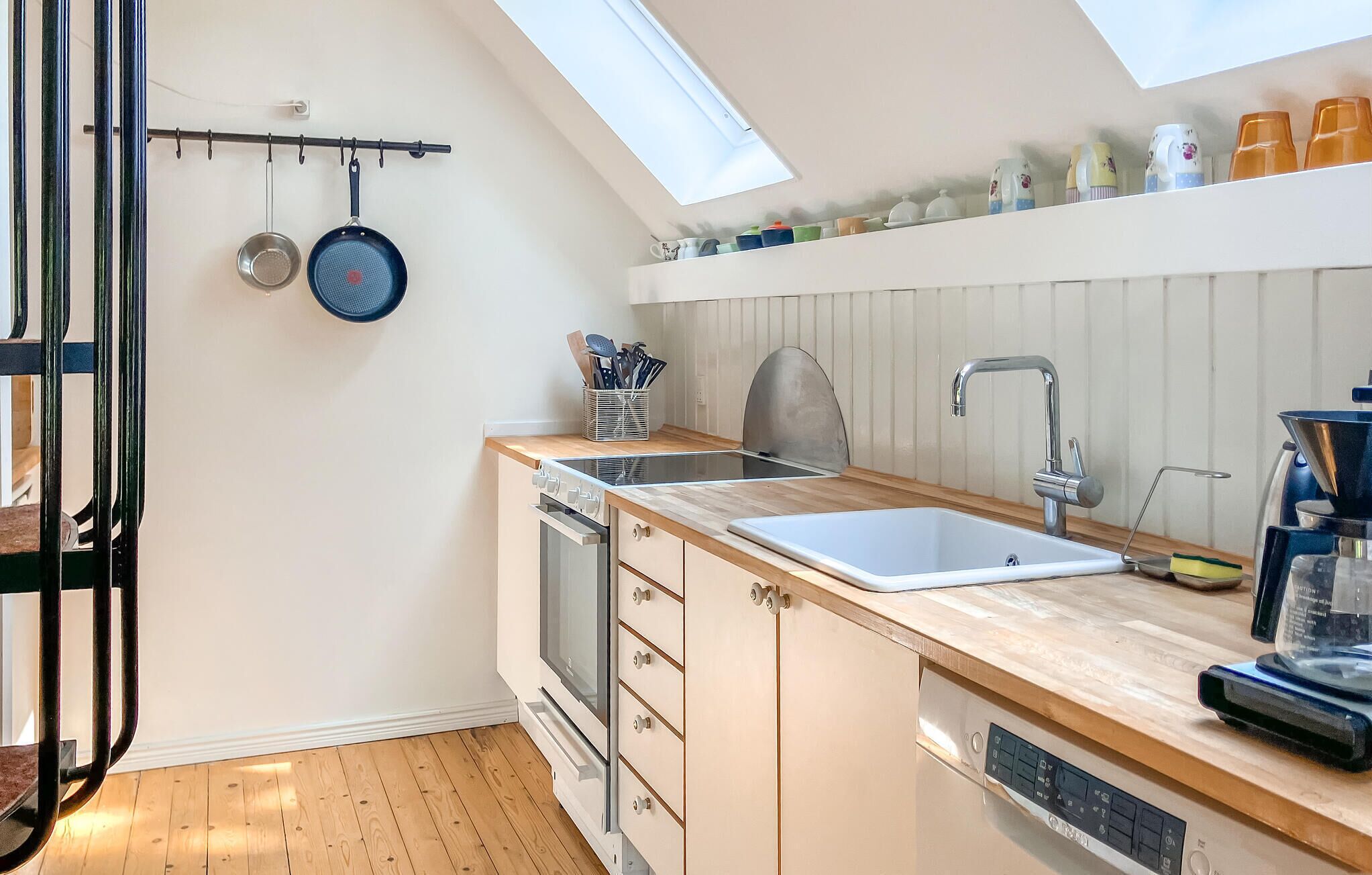 A compact kitchen with a skylight, a built-in oven, a dishwasher, and a sink.