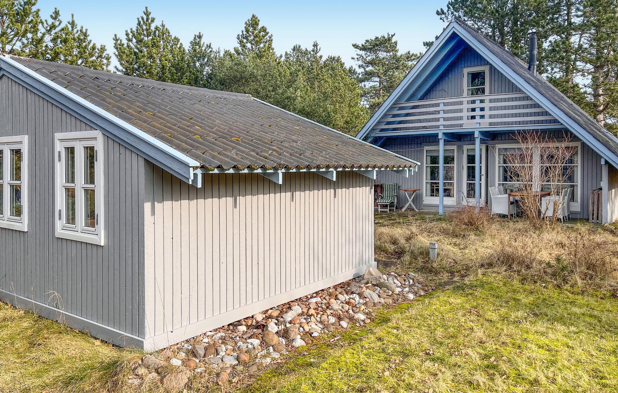 A small wooden cabin with a sloped roof and a separate shed with a blue roof.