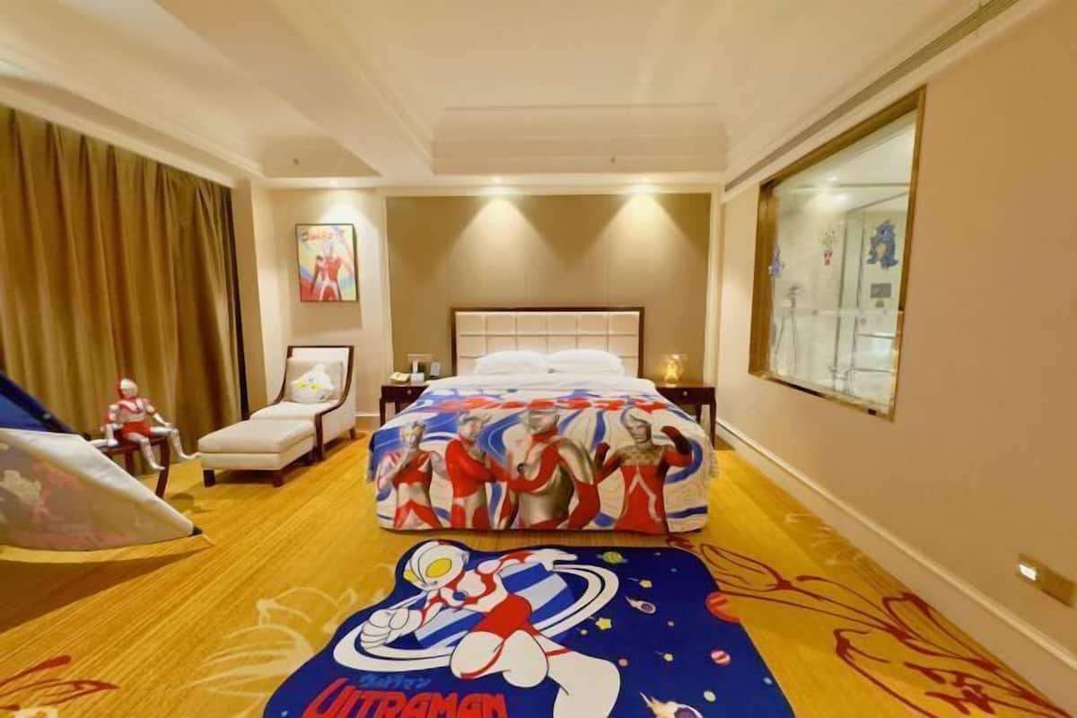 A hotel room with a bed, a chair, a desk, and a large window.