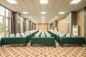 Un salón de conferencias con filas de mesas, sillas y botellas de agua.