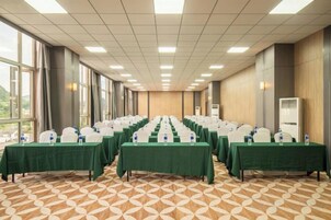 Un salón de conferencias con filas de mesas, sillas y botellas de agua.