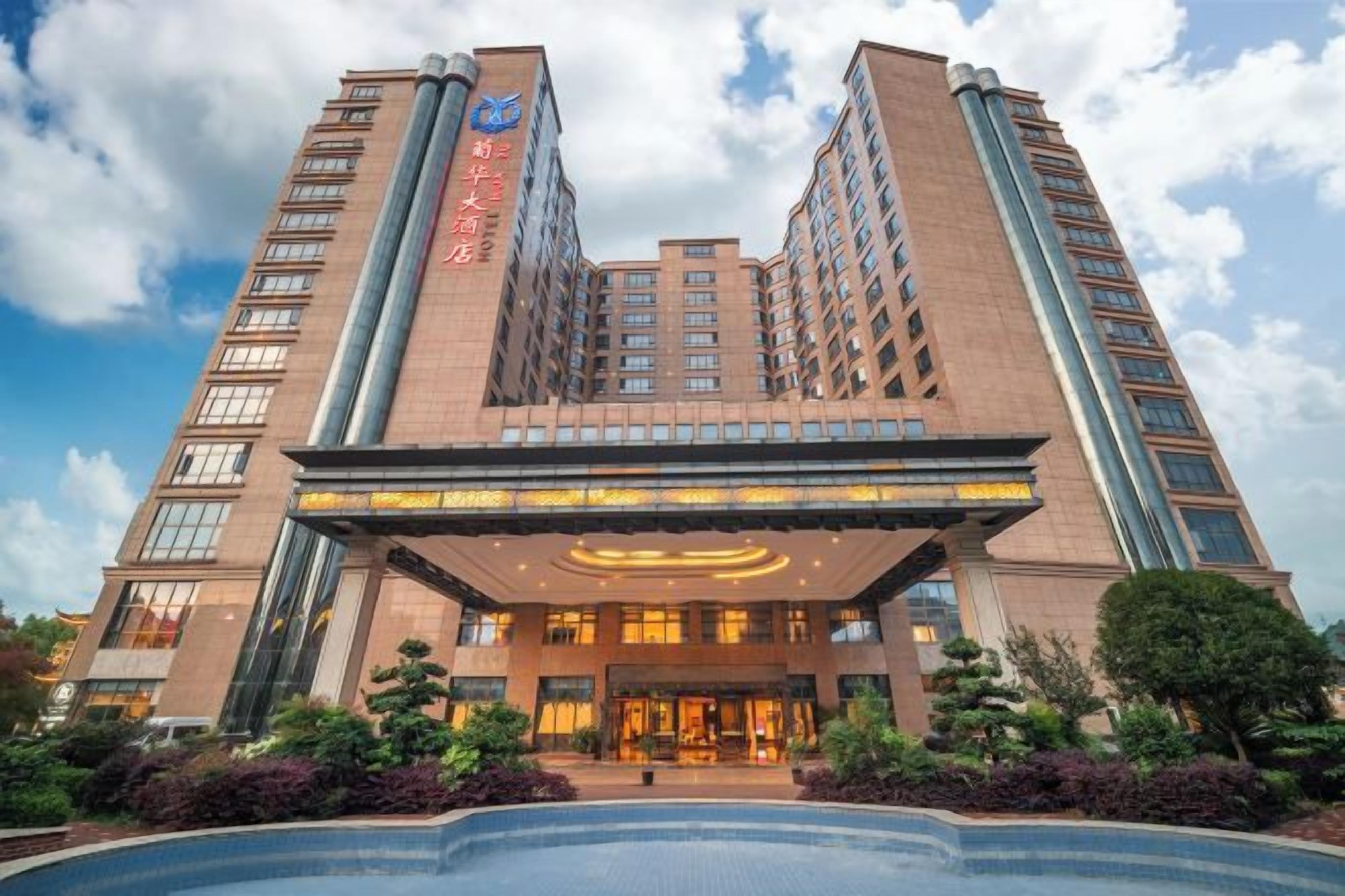 A multi-story hotel with a prominent entrance and a swimming pool.