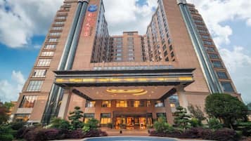 A multi-story hotel with a prominent entrance and a swimming pool.