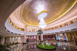 A spacious lobby with a central fountain, high ceilings, and a modern chandelier. - Puhua Hotel (Anshun)