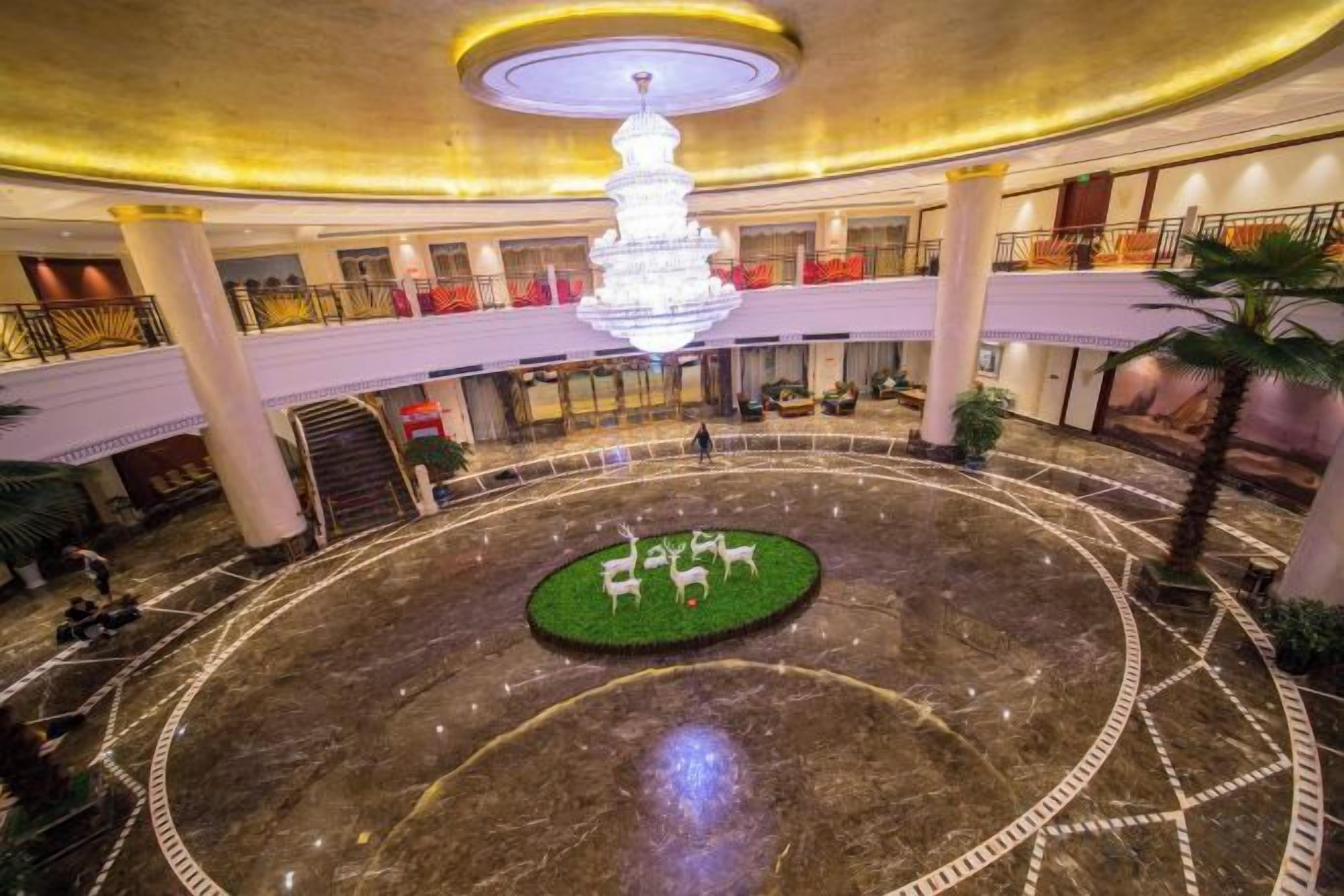 A hotel lobby with a central circular area featuring a fountain, surrounded by a marble floor with geometric patterns.