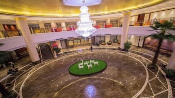 A hotel lobby with a central circular area featuring a fountain, surrounded by a marble floor with geometric patterns.